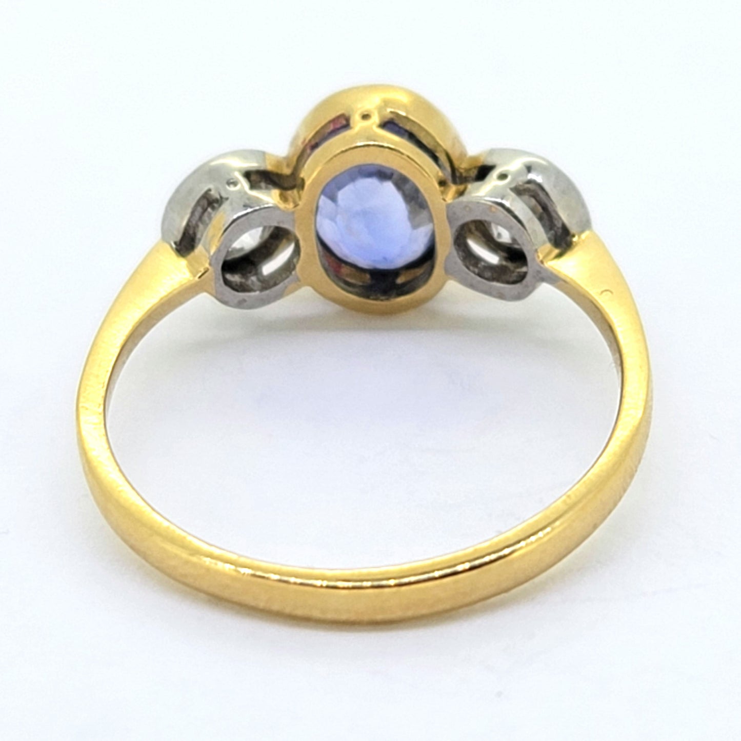 A three stone sapphire and diamond ring in yellow and white gold, on a white background