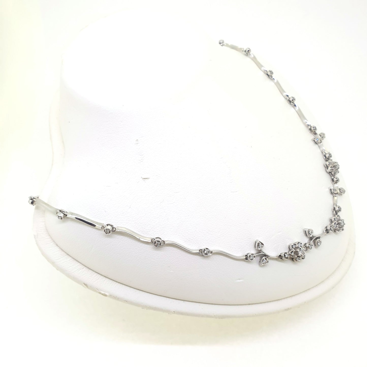 A floral diamond necklace in 14ct white gold, on a neck bust, on a white background