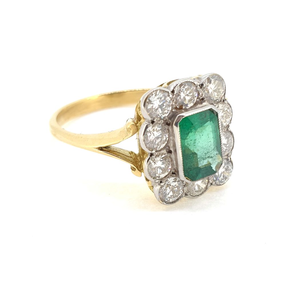 An emerald and diamond rubover set cluster ring in yellow and white gold