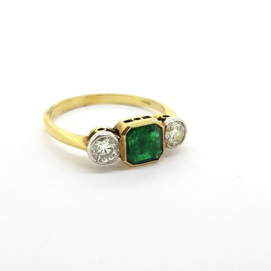 Emerald and Diamond Three Stone Ring; central octagonal step-cut emerald flanked by brilliant cut diamonds, 18ct yellow gold band