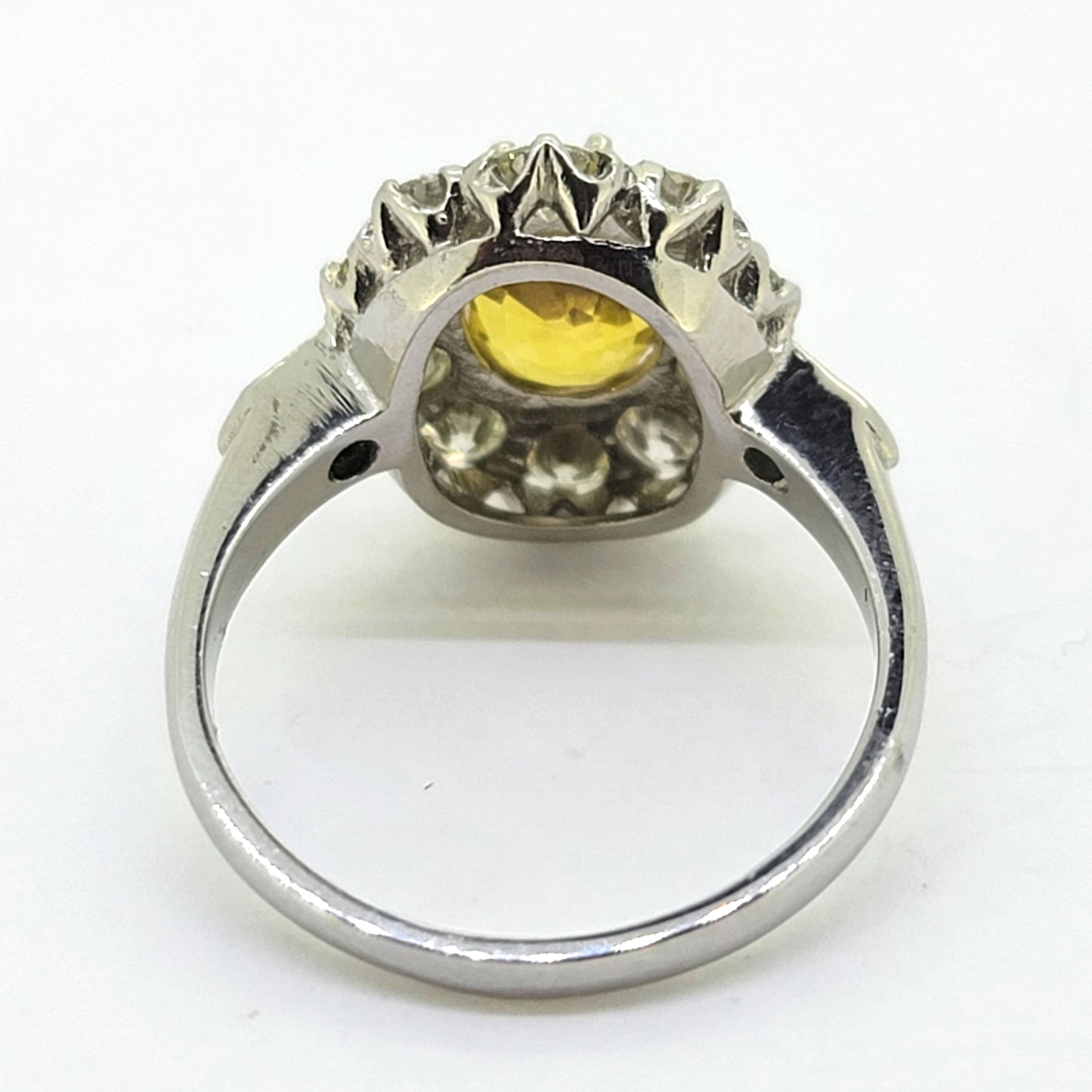 An oval yellow sapphire and round diamond cluster ring in platinum