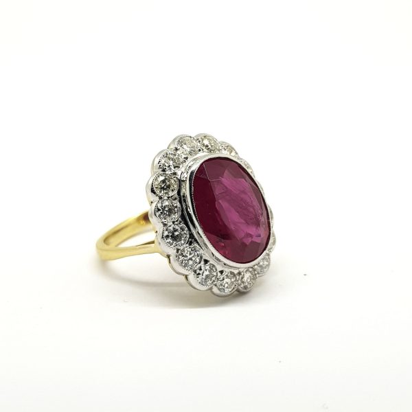 Ruby and Diamond Oval Floral Cluster Ring; featuring a large 7.03ct oval faceted ruby surrounded by 1.35cts diamonds, in 18ct gold