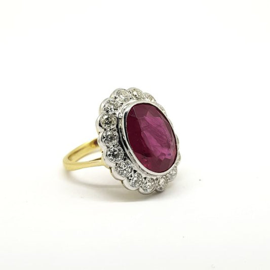Ruby and Diamond Oval Floral Cluster Ring; featuring a large 7.03ct oval faceted ruby surrounded by 1.35cts diamonds, in 18ct gold