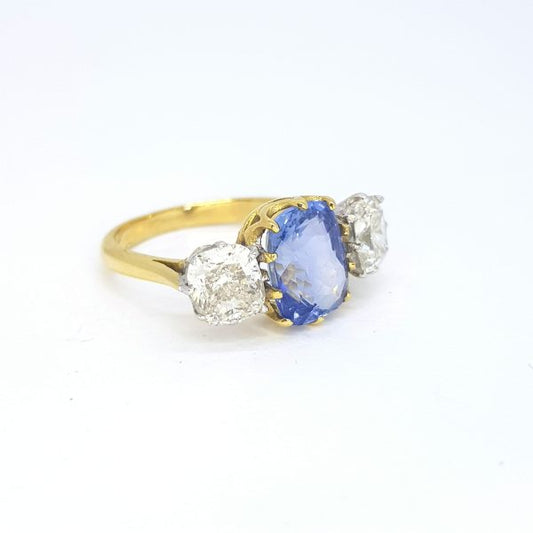 Cushion Cut Sapphire and Diamond Three Stone Ring; featuring a 3.12ct cushion-cut sapphire flanked by 2.15cts cushion-cut diamonds, in 18ct yellow gold