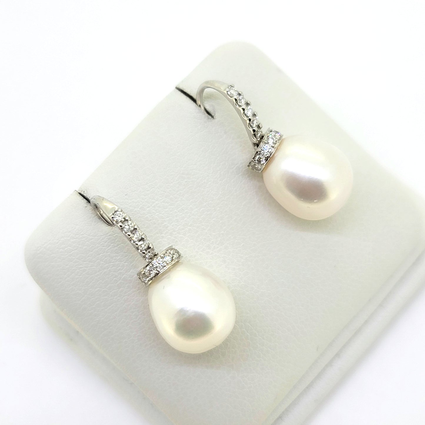 Pearl and diamond drop earrings in white gold, on an earring display pad