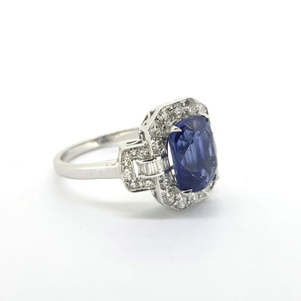 Sapphire and Diamond Cluster Dress Ring; central 3.46ct oval sapphire enclosed within a surround of 0.71cts bright white brilliant and baguette-cut diamonds with detailed 'lock' shoulders, in 18ct white gold