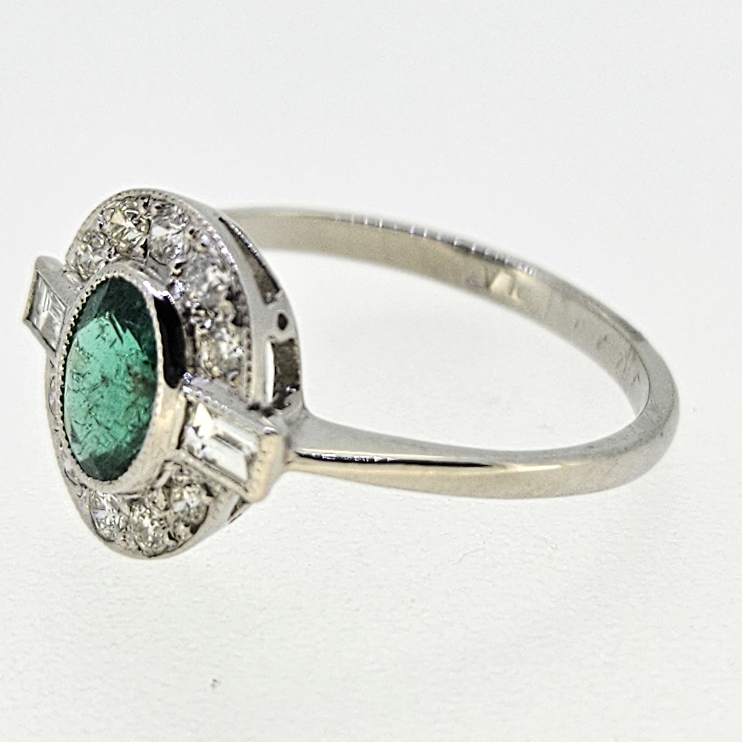 An oval emerald and diamond cluster ring in platinum
