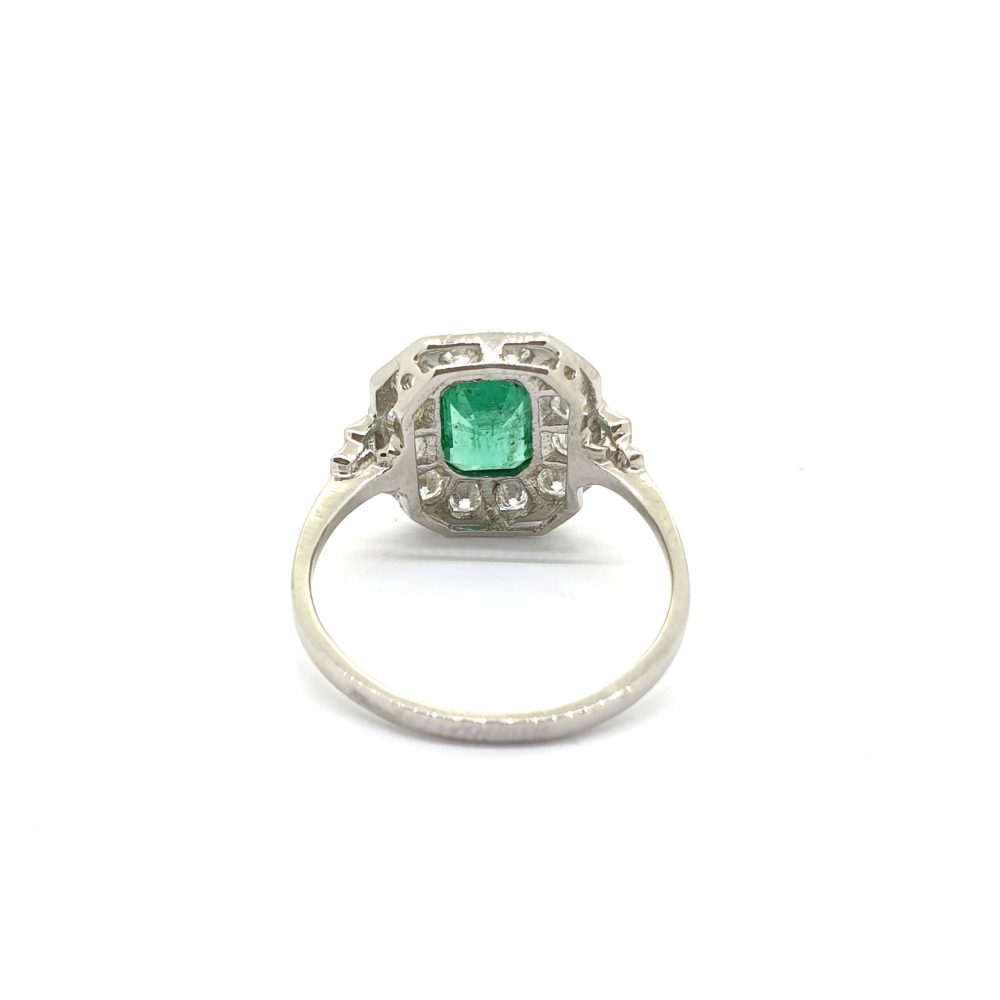 An octagonal cluster ring with an emerald centre and diamond surround, in platinum