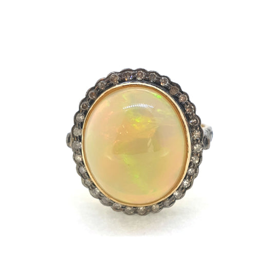 A cabochon opal and diamond oval cluster ring in gold and silver, on a white background
