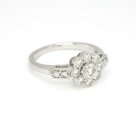 Diamond Daisy Cluster Ring; central brilliant cut diamond surrounded by eight further diamonds, accented with two diamonds on each shoulder, in 18ct white gold