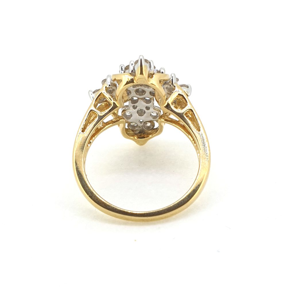 A fancy shaped diamond cluster ring in yellow and white gold, against a white background