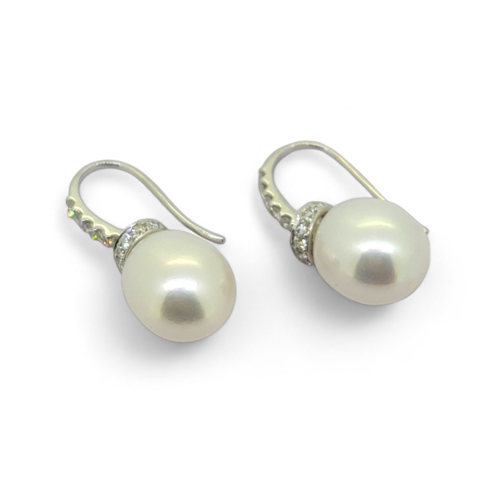 A pair of pearl and diamond drop earrings in white gold with hook fittings, against a white background