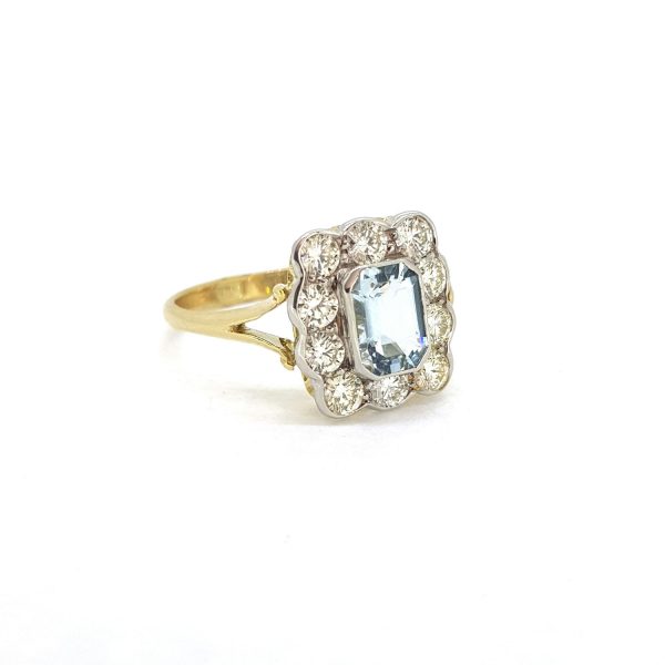 Aquamarine and Diamond Floral Cluster Ring; 0.75ct emerald-cut aquamarine surrounded by 0.90cts brilliant-cut diamonds, collet set in white gold and mounted to 18ct yellow gold shank with split shoulders