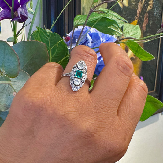 A navette shaped emerald and diamond ring in white gold, modelled on a hand