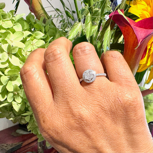 A white gold diamond halo cluster ring, modelled on a hand