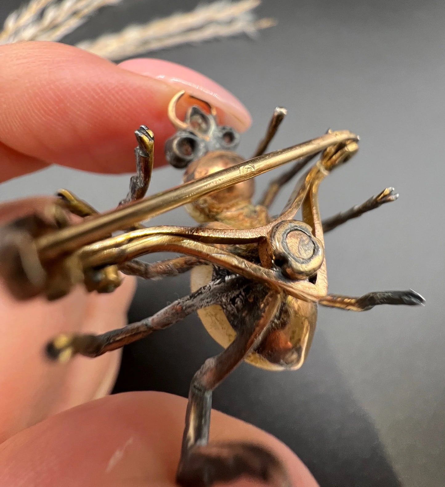 A pearl and diamond spider brooch in gold and silver, held in a hand
