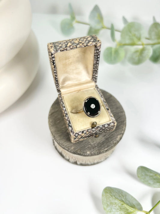 An oval black onyx and diamond ring in white and rose gold, in a box