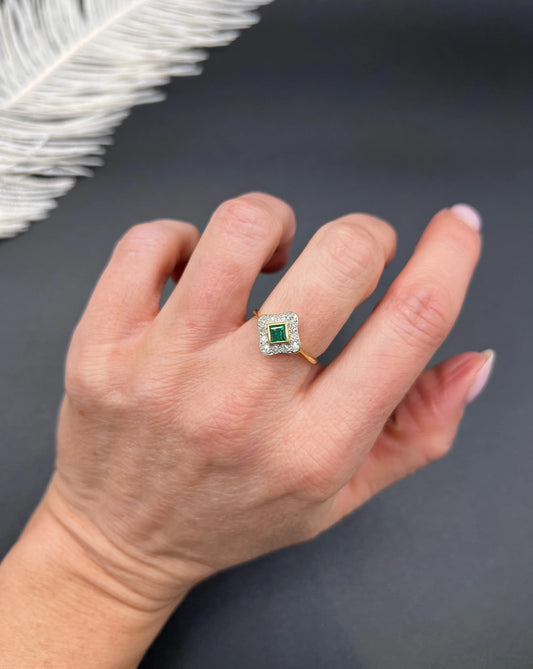 An emerald and diamond cluster ring in yellow gold and platinum, modelled on a hand
