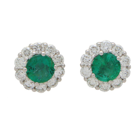Emerald and diamond cluster earrings set in white gold.