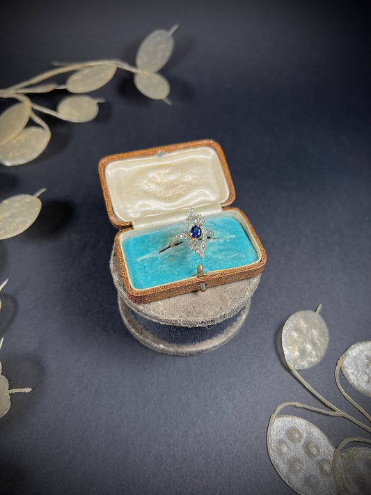 A navette shaped sapphire and diamond cluster ring, in an antique jewellery box