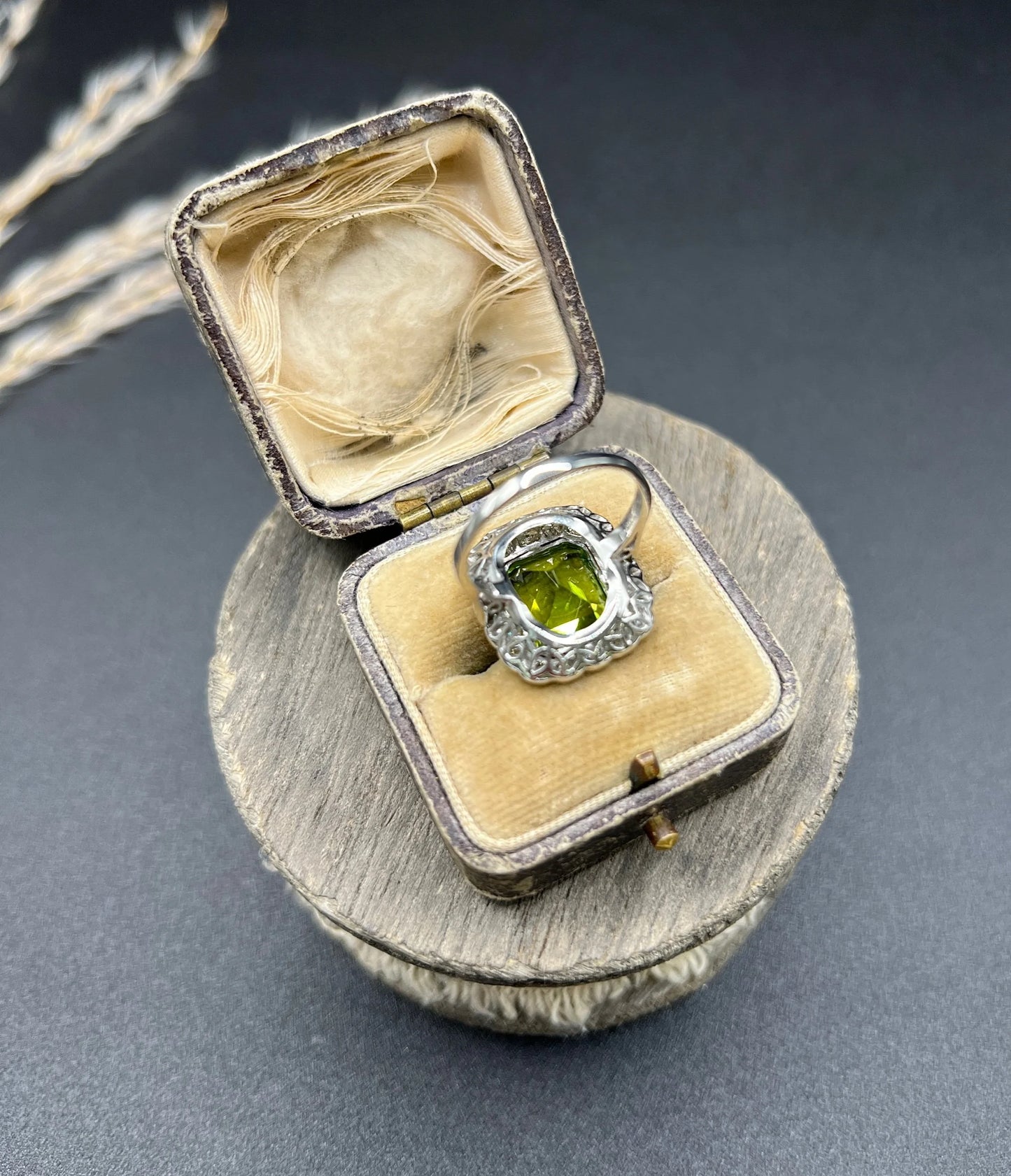 A cushion shaped peridot and diamond cluster ring in white metal, in an antique ring box
