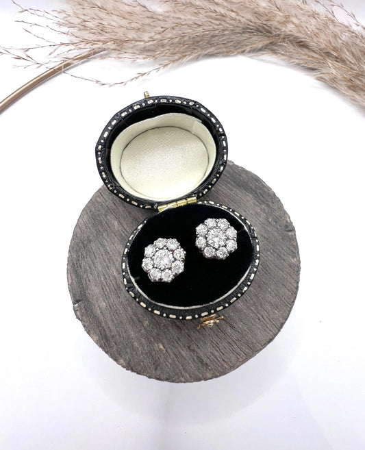 A pair of diamond daisy cluster stud earrings in yellow and white gold, in an earring box