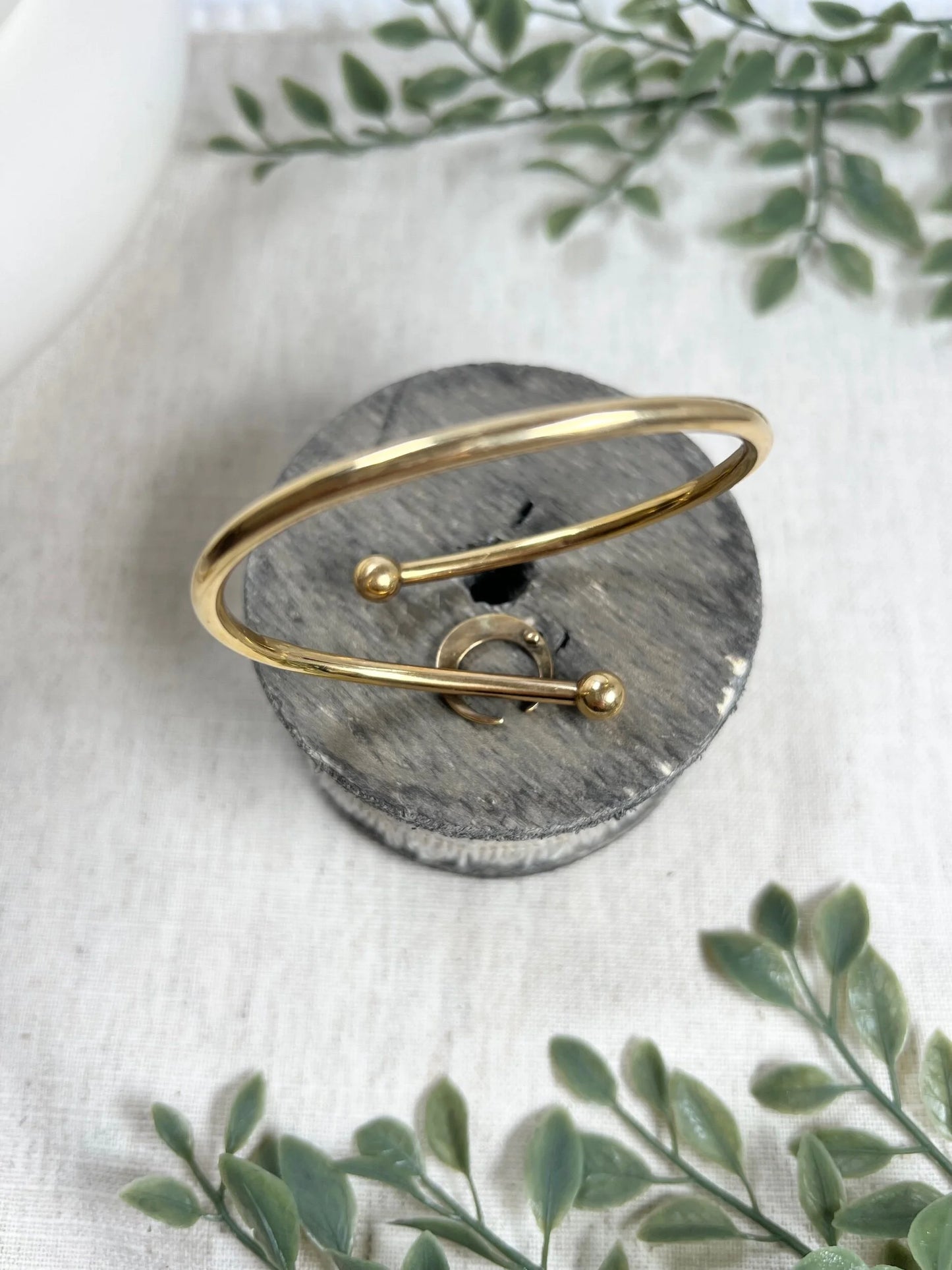 A yellow gold crossover bangle bracelet with a pearl and turquoise crescent moon centre