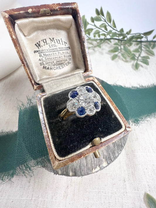 A sapphire and old cut diamond cluster ring in gold, in an antique ring box