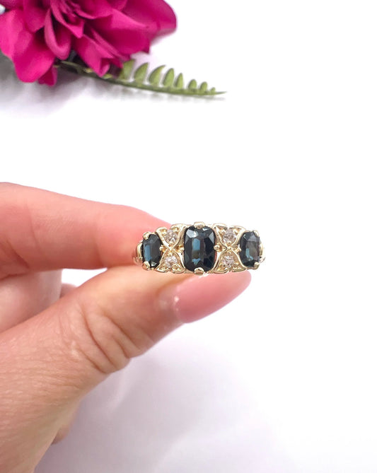 A seven stone sapphire and diamond carved ring in yellow gold, held in a hand