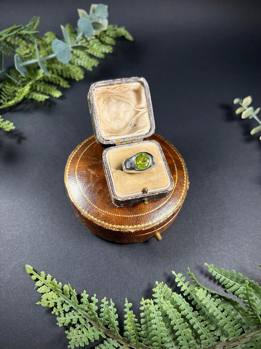 A peridot and diamond five stone band ring in white metal, in an antique ring box