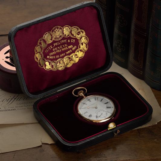 A yellow gold Patek Phillipe pocket watch with white dial and black Roman numerals, in a Patek Phillipe fitted case