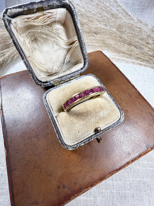 A yellow gold ruby channel set eternity band, in an antique ring box