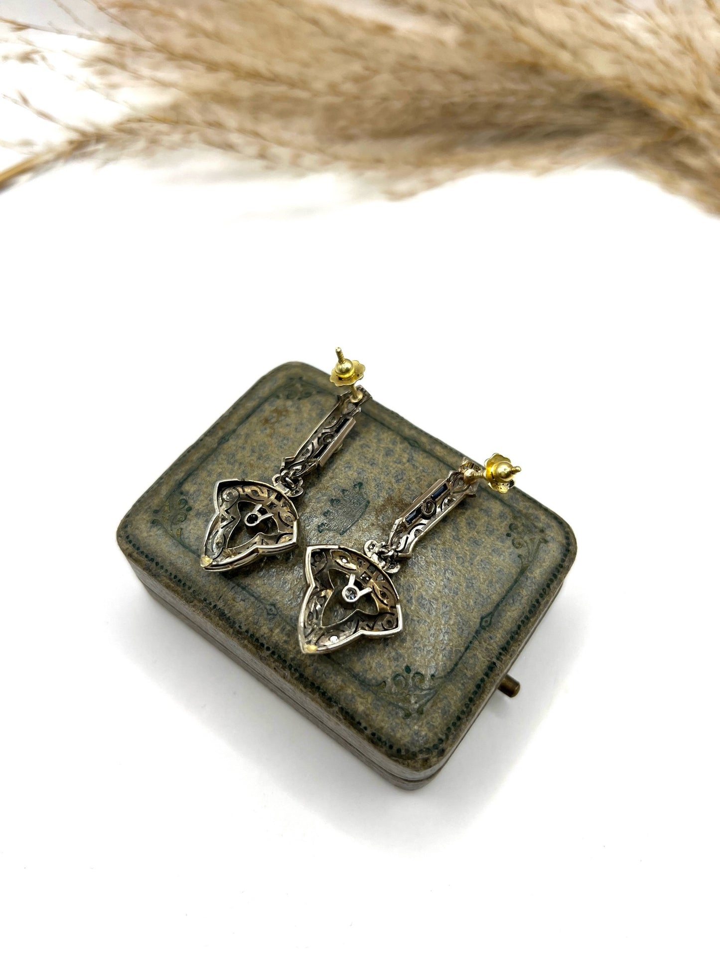 A pair of diamond and sapphire drop earrings, on an antique box