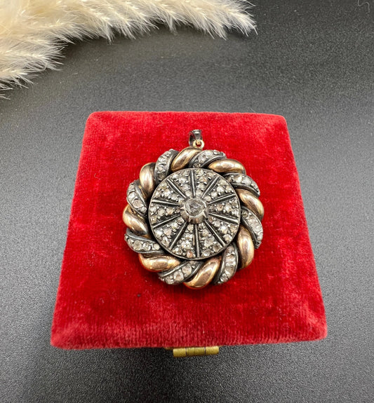 A pinwheel design pendant in gold and platinum with diamonds, on a red antique box