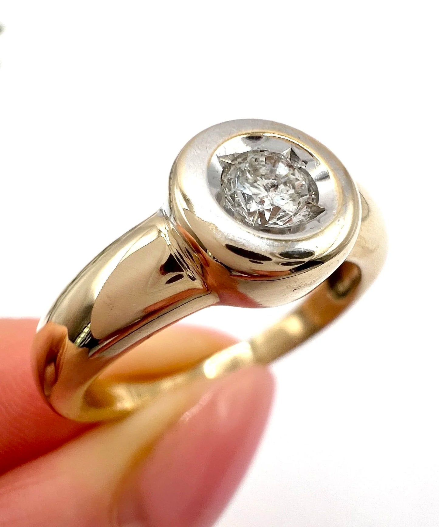 A single stone brilliant cut diamond ring bezel set in yellow gold, close-up
