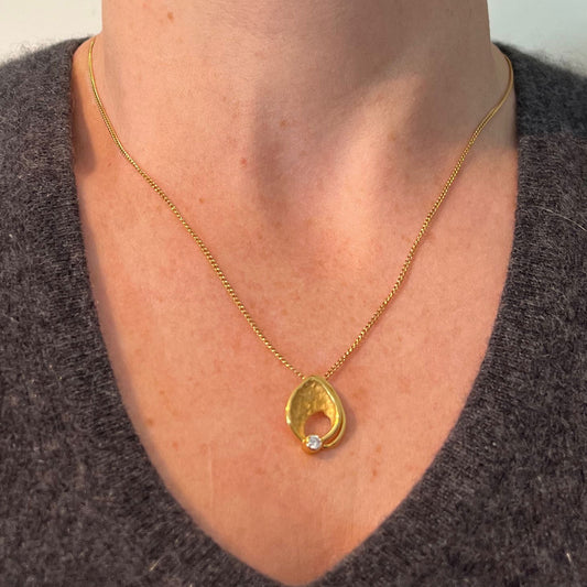 A yellow gold leaf shaped pendant with a diamond, modelled on a gold chain