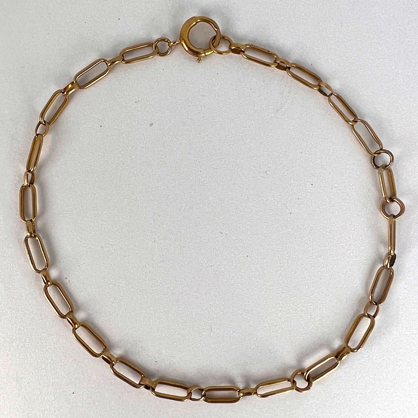 A yellow gold link bracelet with bolt ring clasp, on a white background
