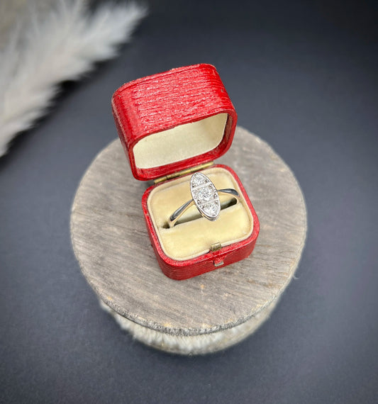 An oval shaped ring set with three round diamonds mounted in platinum, in a red antique ring box