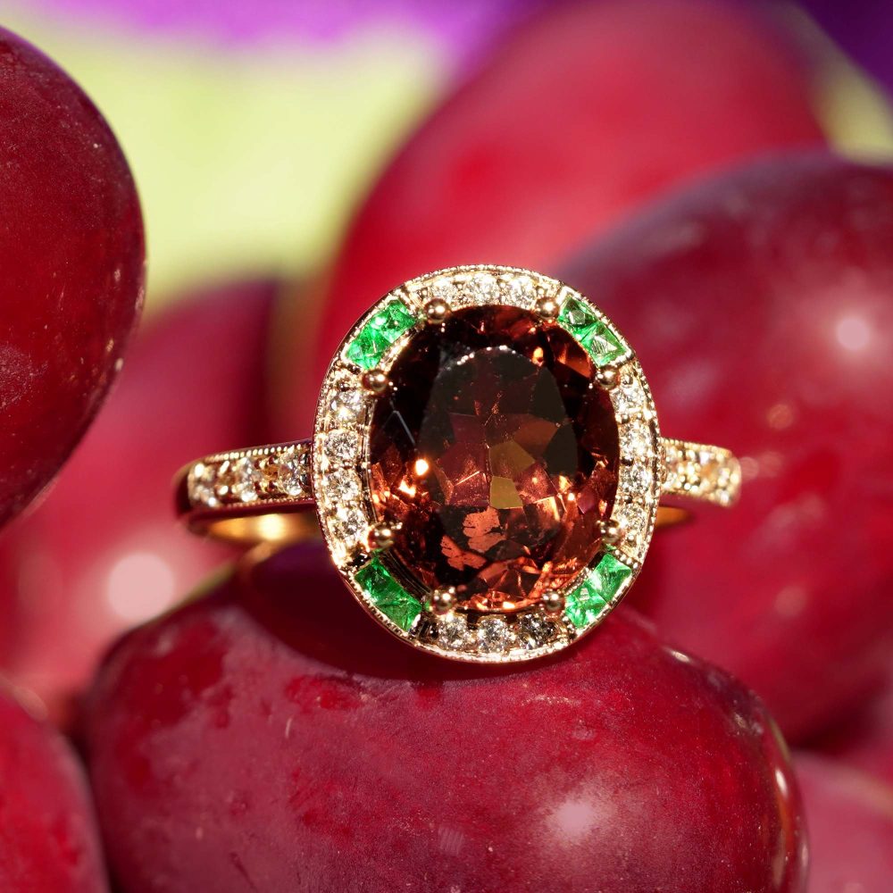 3.88ct Oval Pink Tourmaline Emerald Diamond Cluster Engagement Ring, 3.88ct oval pink tourmaline surrounded by halo of diamonds with emerald accents in 14ct rose gold