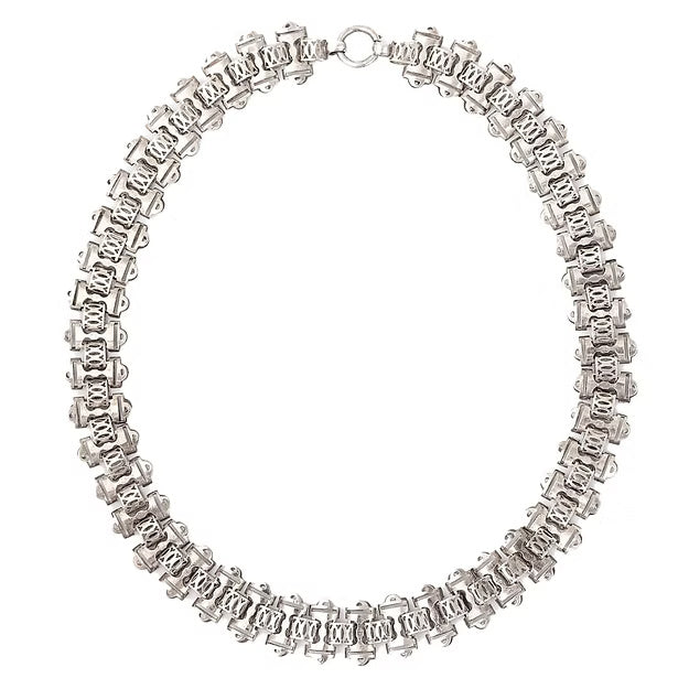 Victorian silver collar necklace featuring engraved flat links, foliate connectors, and heart-shaped details, circa 1880.