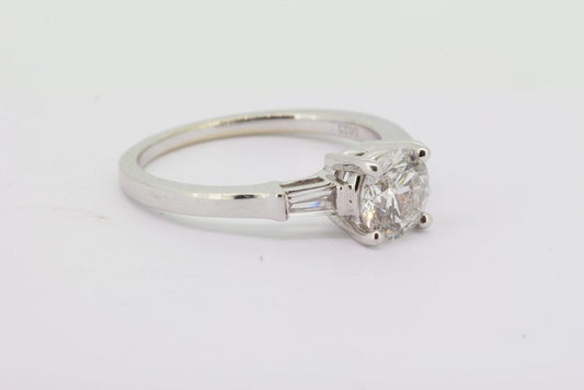 Diamond Solitaire Engagement Ring with Baguette Shoulders; central 0.98ct round brilliant-cut diamond, four claw set, and flanked by collet set tapered baguette-cut diamonds to the shoulders, in 18ct white gold