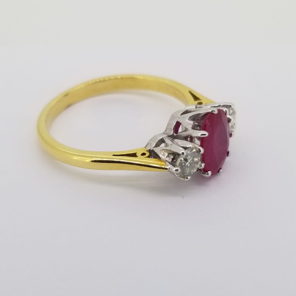 Ruby and Diamond Three Stone Ring; central oval faceted ruby flanked by brilliant-cut diamonds, in 18ct yellow gold
