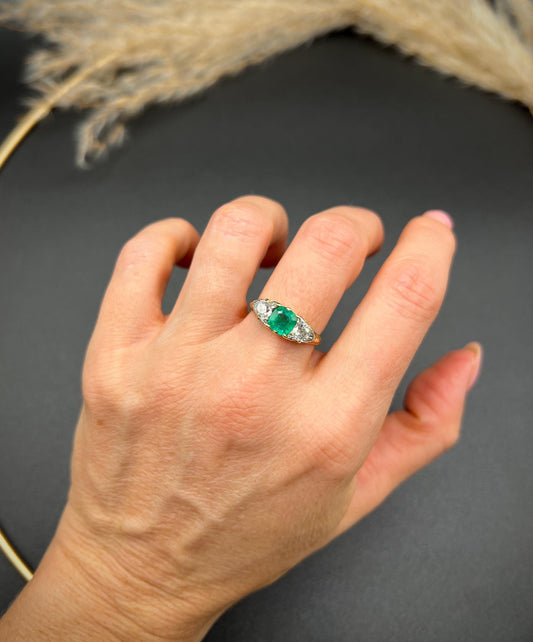 A three stone old cut emerald and diamond ring in yellow gold, modelled on a hand