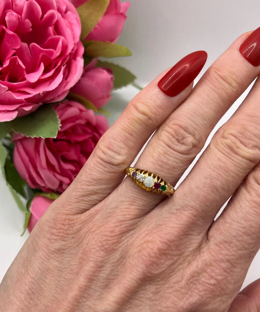 A five stone acrostic ADORE ring in yellow gold, modelled on a hand