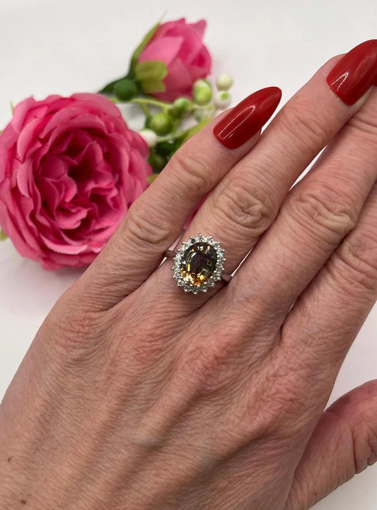 An oval tourmaline and diamond cluster ring in white gold, modelled on a hand