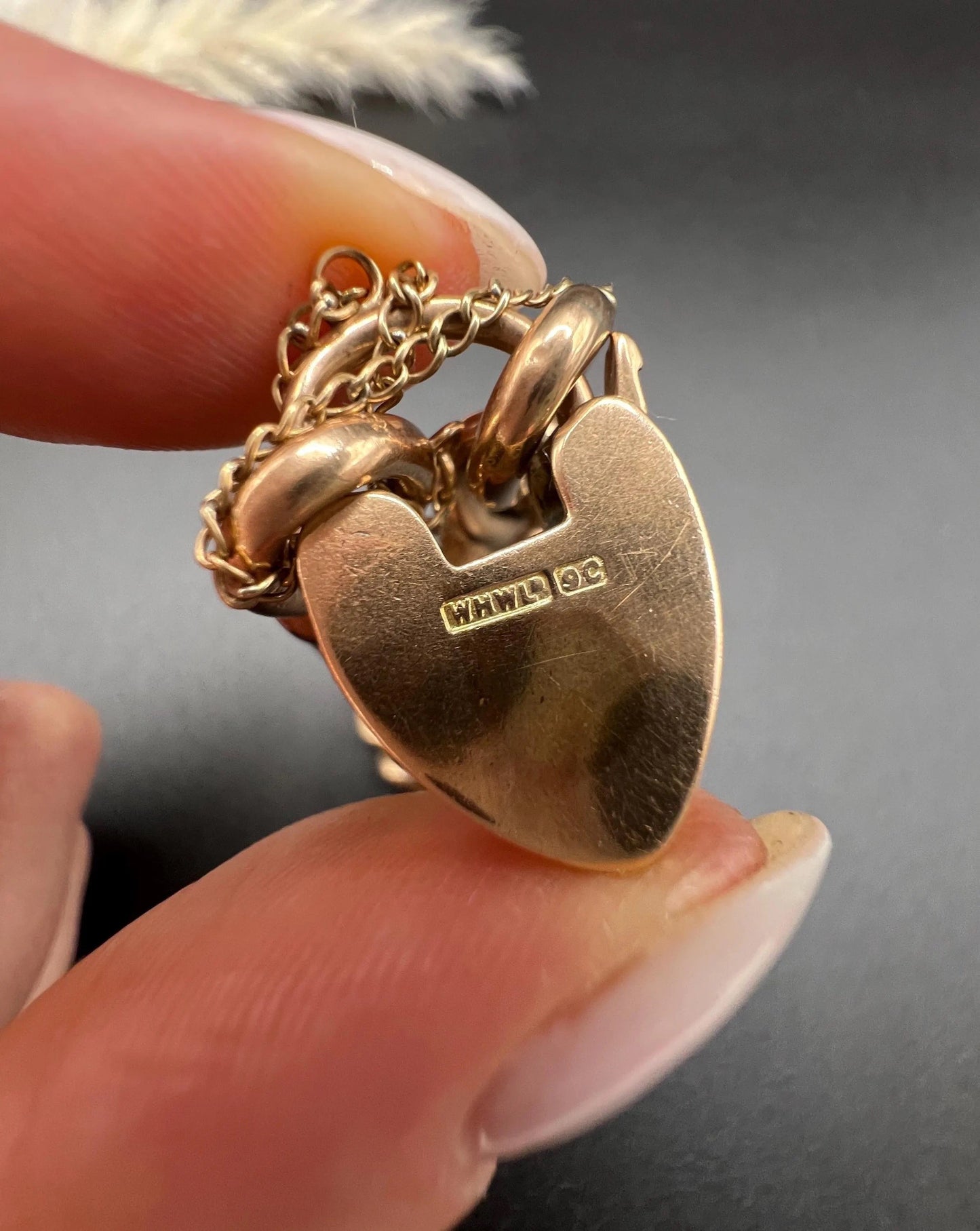 Close-up of stamps on a gold heart shaped padlock clasp
