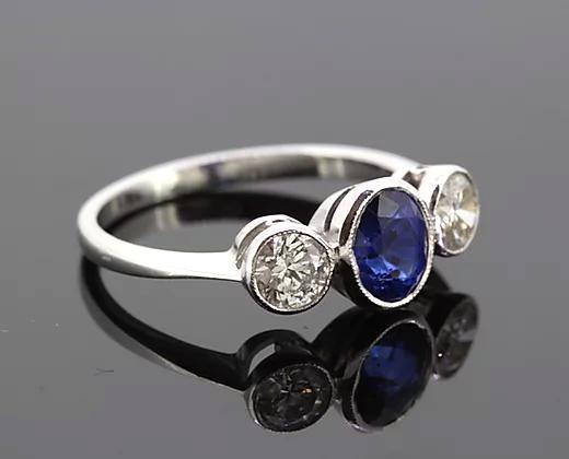 Oval Sapphire and Diamond Trilogy Ring; three-stone ring featuring 1.15ct oval-cut sapphire flanked by two diamonds totaling 0.67cts, 18ct white gold