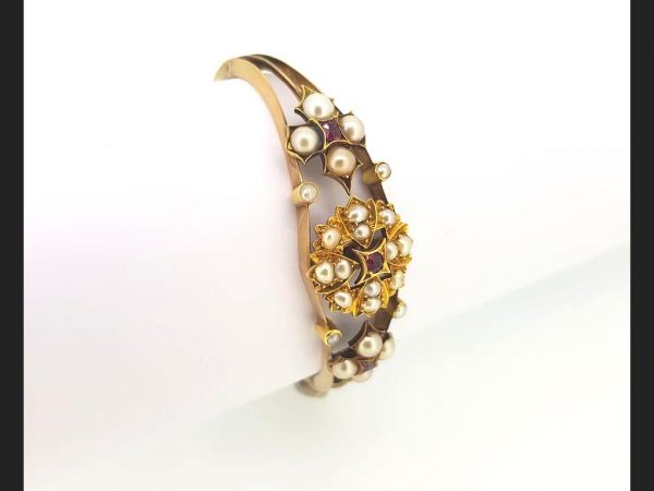 An Antique Edwardian Split Pearl and Ruby Bangle with central floral design and flanked by similar design, on detailed 15ct gold bangle