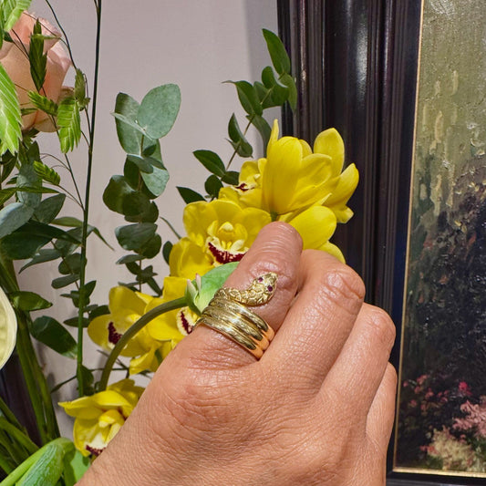A yellow gold coiled snake ring with ruby eyes modelled on a hand