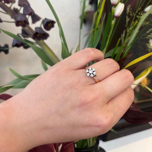 A diamond cluster ring in rose and white gold, modelled on a hand